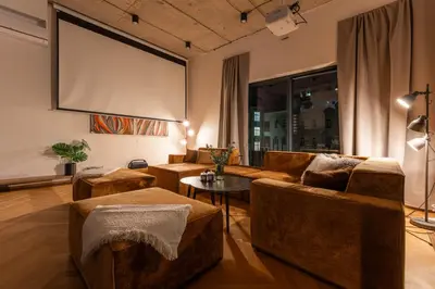 a living room with brown furniture and a large screen at Luxury Oomph Apartments in Prague