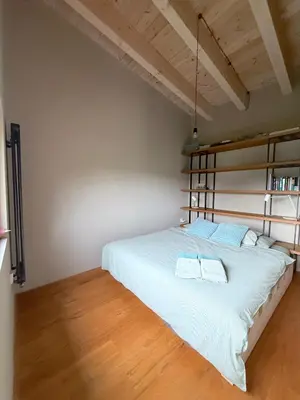 a bedroom with a large white bed with a wooden floor at Chata Nola Slapy in Křečovice