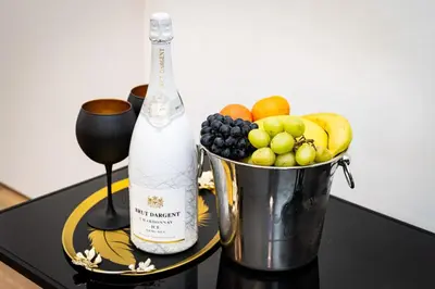a bottle of champagne and a bucket of fruit on a table at Red Rose Residence in Prague