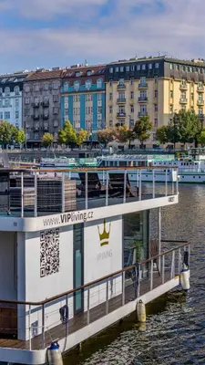 a ferry boat in the water with buildings in the background at VIPliving Houseboat in Prague