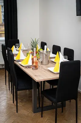 a dining room table with chairs and a table with yellow napkins at Victory Belle Maison in Prague