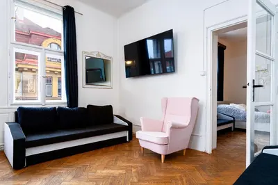 a living room with a black couch and a pink chair at Victory Belle Maison in Prague