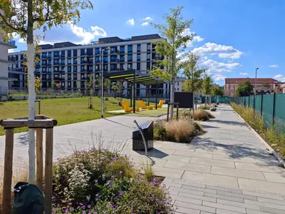 a park with a bench and a building in the background at Kolbenova Comfort Stay in Prague