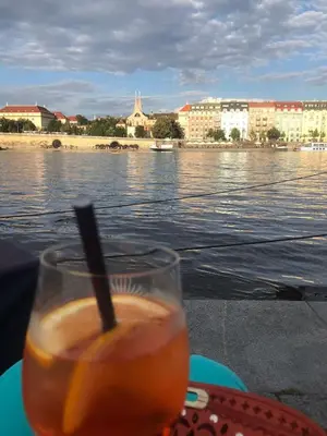 a drink sitting on a table next to the water at Prague central 3&kk apartment Andel in Prague