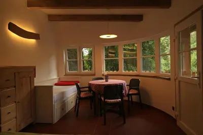a dining room with a table and chairs and windows at Malběnka - chata na skále pod hradem Kokořín in Kokořín