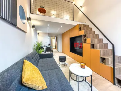 a living room with a couch and a staircase at New Modern Art Loft Apartment, City Center in Prague