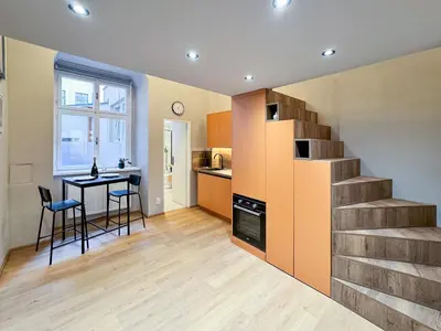 a kitchen with a staircase and a table and chairs at New Modern Art Loft Apartment, City Center in Prague