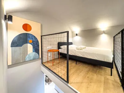 a small bedroom with a bed and a staircase at New Modern Art Loft Apartment, City Center in Prague