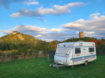 an rv parked in a field in front of a hill at Kempování s výhledem na hrady in Zdice