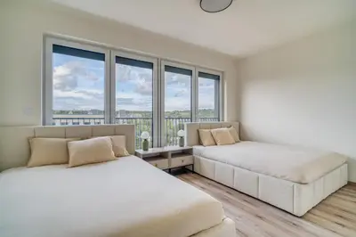 two beds in a room with large windows at Chloé's Beige Apartment with big balcony, O2 arena in Prague