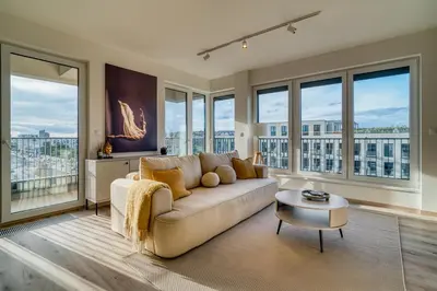 a living room with a couch and large windows at Chloé's Beige Apartment with big balcony, O2 arena in Prague