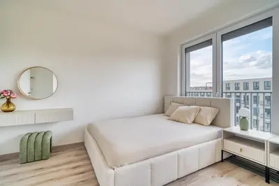 a white bedroom with a bed and a mirror at Chloé's Beige Apartment with big balcony, O2 arena in Prague