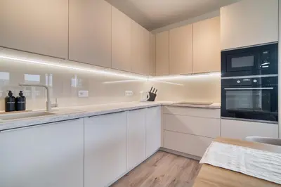 a kitchen with white cabinets and black appliances at Chloé's Beige Apartment with big balcony, O2 arena in Prague