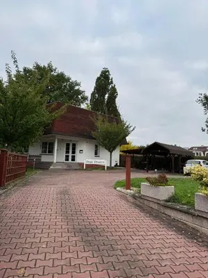 a white building with a red roof and a brick driveway at Park Pension