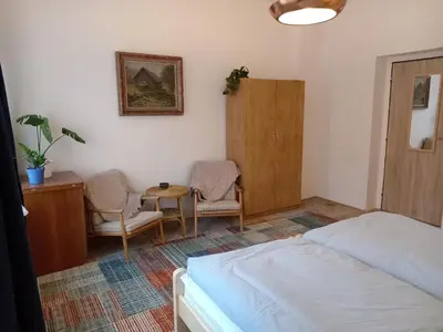 a bedroom with a bed and two chairs and a table at Apartmán Na Leštině in Příbram