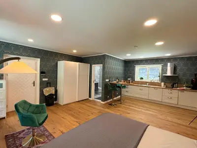 a large kitchen with a green chair and a table at Mulino Apartments