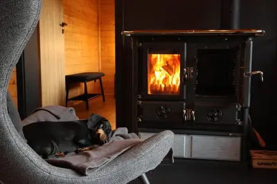 a dog laying in a chair in front of an oven at Chata Cedrus in Hradištko