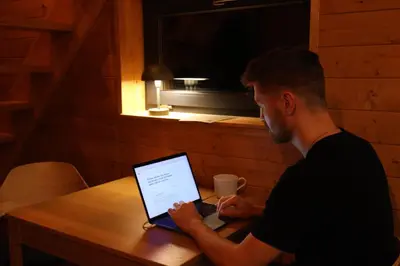 a man sitting at a table using a laptop computer at Chata Cedrus in Hradištko