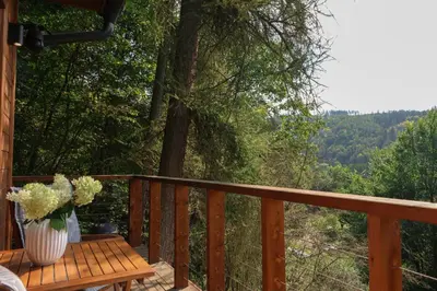 a wooden balcony with a table and vases of flowers at Chata Cedrus in Hradištko