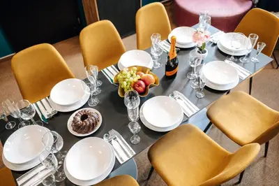 a dining table with white dishes and a bowl of fruit at Smichov MixHause Residence by Wagnerstays in Prague