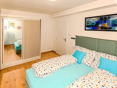 a bedroom with a blue bed and a mirror at Apartment Hanspaulka - Stylish, Parking Included, 15 min Airport in Prague