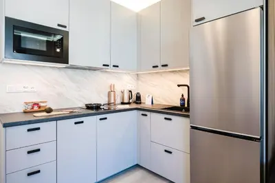 a kitchen with white cabinets and a stainless steel refrigerator at Prague Days - Studio near Vyšehrad with Netflix and 250Mbs WiFi in Nusle in Prague