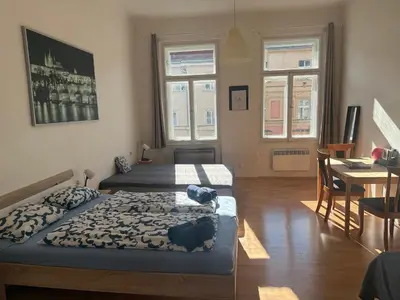 a room with two beds and a table and two windows at Johan apartments in old Vinohrady in Prague