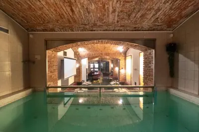 a swimming pool in a house with a brick wall at Party ClubHouse with Bar, Panoramic Pool & Sauna in Prague
