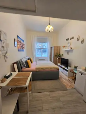 a living room with a table and a kitchen with a bed at Get Prague Flat Slovenska in Prague