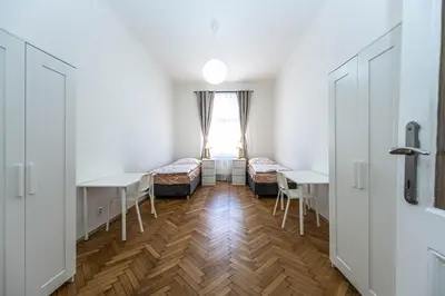 a room with two beds and tables and a window at Apartments Rehorova 30 in Prague