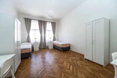 a bedroom with two beds and two windows at Apartments Rehorova 30 in Prague