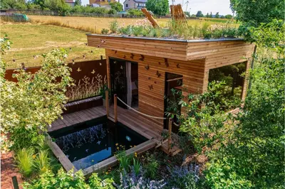 a small wooden house with a pond in a garden at Apartmán Rezidence Malá Louka in Kublov