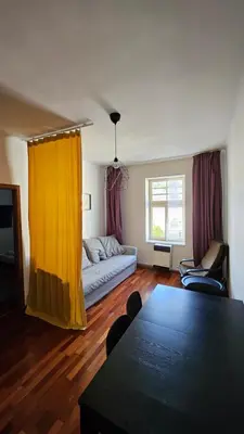 a living room with a table and a yellow curtain at Zizkov Apartment in Prague