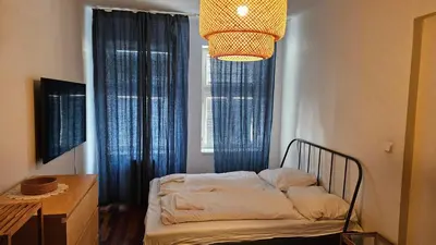 a bedroom with a bed with blue curtains and a chandelier at Zizkov Apartment in Prague