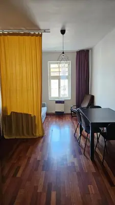 a living room with a table and a yellow curtain at Zizkov Apartment in Prague