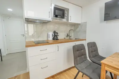 a kitchen with white cabinets and a table and chairs at HOMELY I Central 28m2 loft I ELEVATOR I Self Check-In in Prague