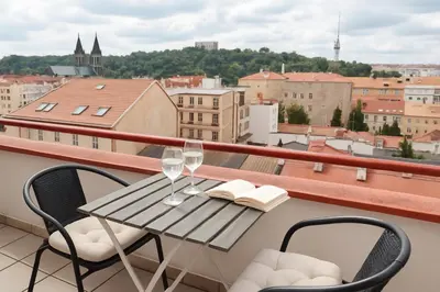a table with wine glasses and books on a balcony at Penthouse With City Terrace in Prague