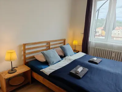 a bedroom with a bed with blue sheets and a window at Penthouse With City Terrace in Prague