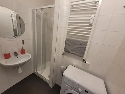 a white bathroom with a sink and a washing machine at Penthouse With City Terrace in Prague