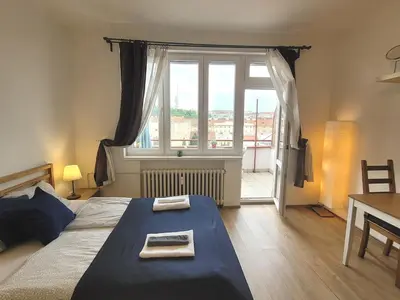 a bedroom with a bed and a large window at Penthouse With City Terrace in Prague