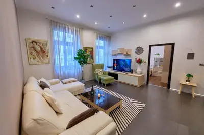 a living room with a white couch and a television at Heart of Prague Stylish 3BR Apartment in Prague
