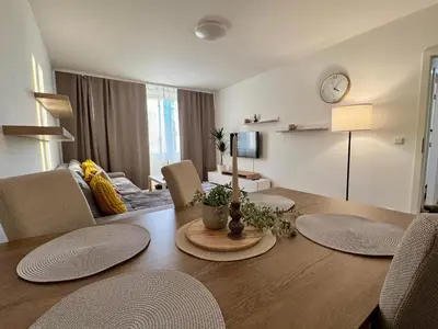 a dining room with a table and a living room at FH Apartment Letňany in Prague