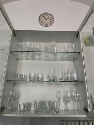 a shelf filled with glasses and a clock on a wall at Apartmán LACRON Praha in Prague