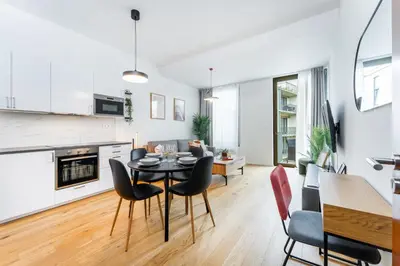 a kitchen and living room with a table and chairs at Rentero Modern Prague Smichov Apartment with Balcony in Prague