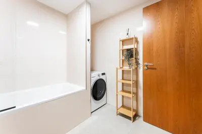 a laundry room with a washing machine and a wooden door at Rentero Modern Prague Smichov Apartment with Balcony in Prague