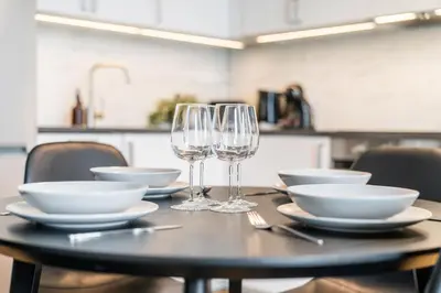 a table with plates and wine glasses on it at Rentero Modern Prague Smichov Apartment with Balcony in Prague
