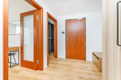 a hallway with two doors and a wooden floor at Rentero Modern Prague Smichov Apartment with Balcony in Prague