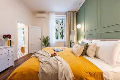 a bedroom with a large bed with a yellow blanket at Prague Days - Apartments with AC in Vinohrady in Prague
