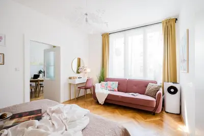 a living room with a pink couch in front of a window at Prague Days - Two Bedroom Apartment with AC next to National Theatre in Prague