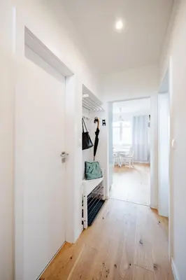 a white hallway with a woman standing on a shelf at Prague Days - One Bedroom Apartment with AC and Workspace in Holešovice in Prague